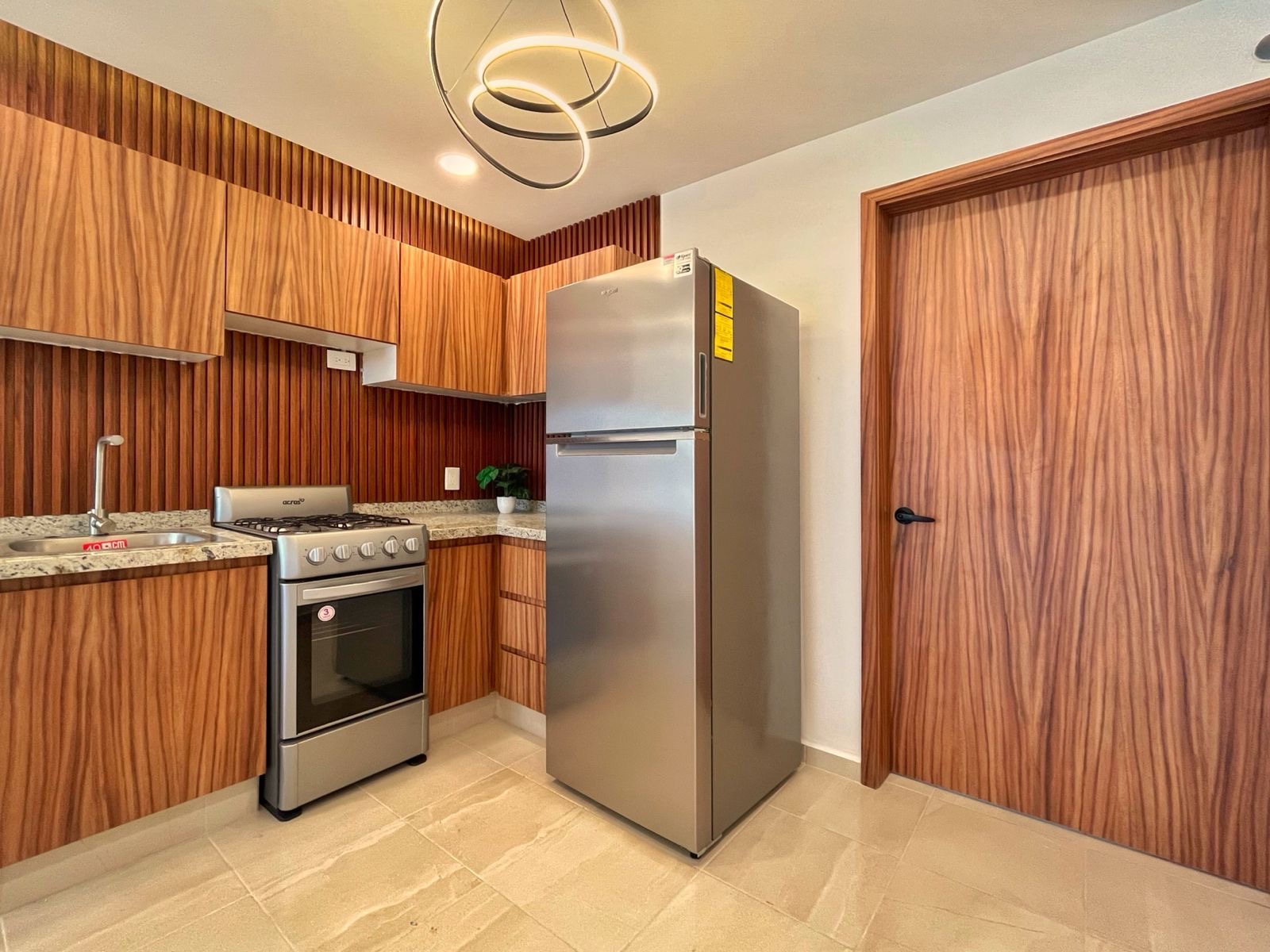 Cocina integral equipada con carpintería en madera, estufa y refrigerador